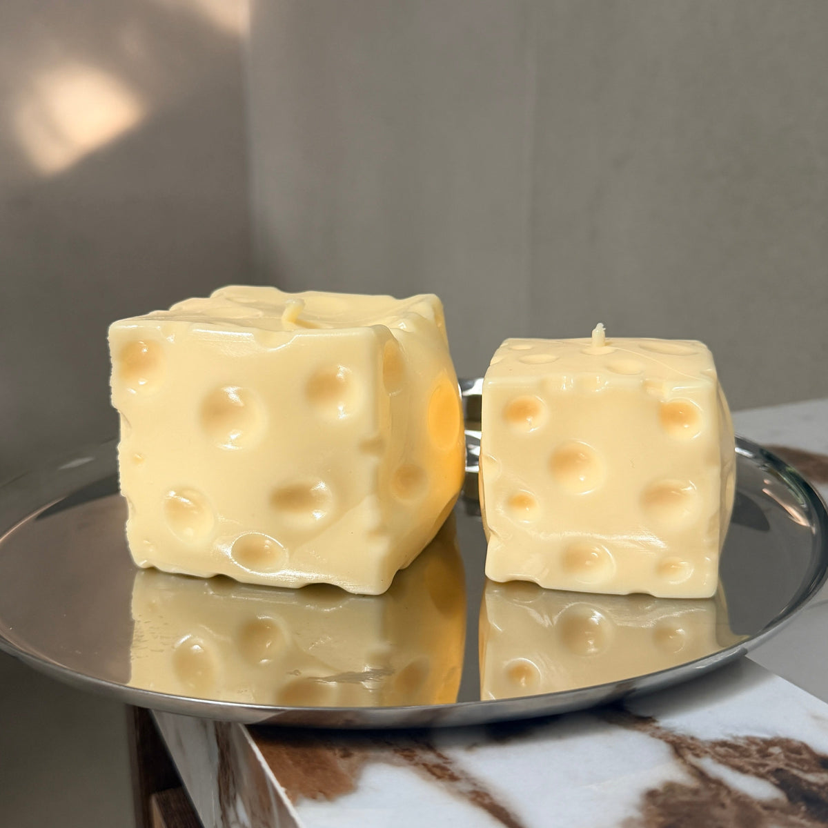 Jumbo and baby cheese squishy stress ball sensory toys displayed side by side on a silver tray.