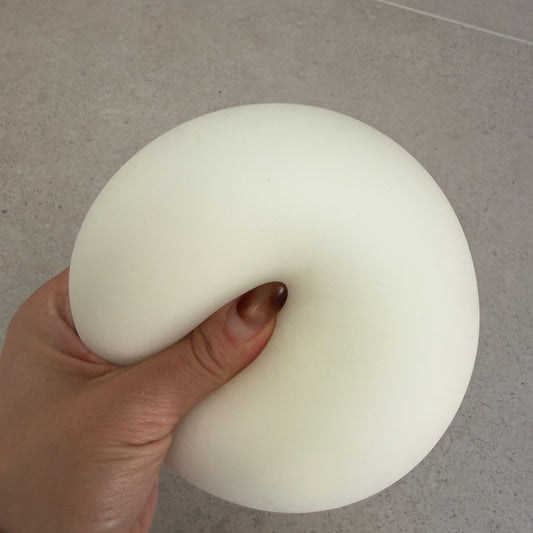 Hand squeezing a 9cm Jumbo Zen squishy stress ball with soft doughy texture, matte finish, and oversized full-hand design.
