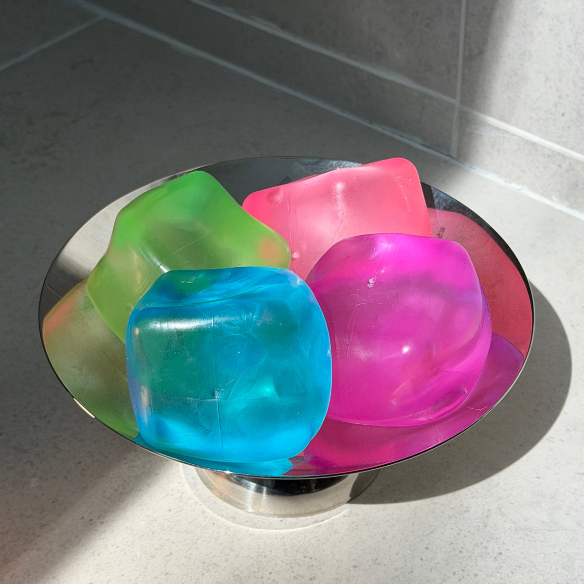 SQUU candy-colored jumbo maltose squishy cubes with slow rebound, displayed in blue, green, pink, and magenta.