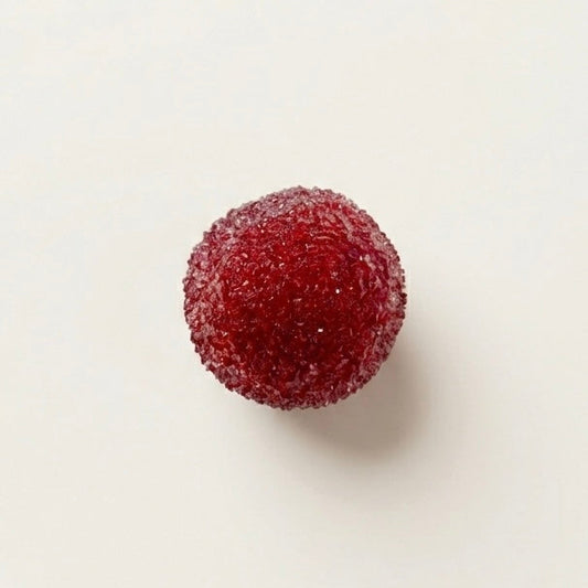 Red berry slushy squishy stress ball. Color is ruby red.  Squishy ball best for asmr fidgets toy. A single red, sugar-coated round candy, resembling a miniature wild strawberry or gummy, centered on a plain off-white background. 