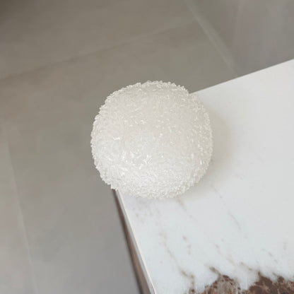 Clear white shaved ice texture ASMR squishy ball with a soft crystal-like surface displayed on a marble countertop.