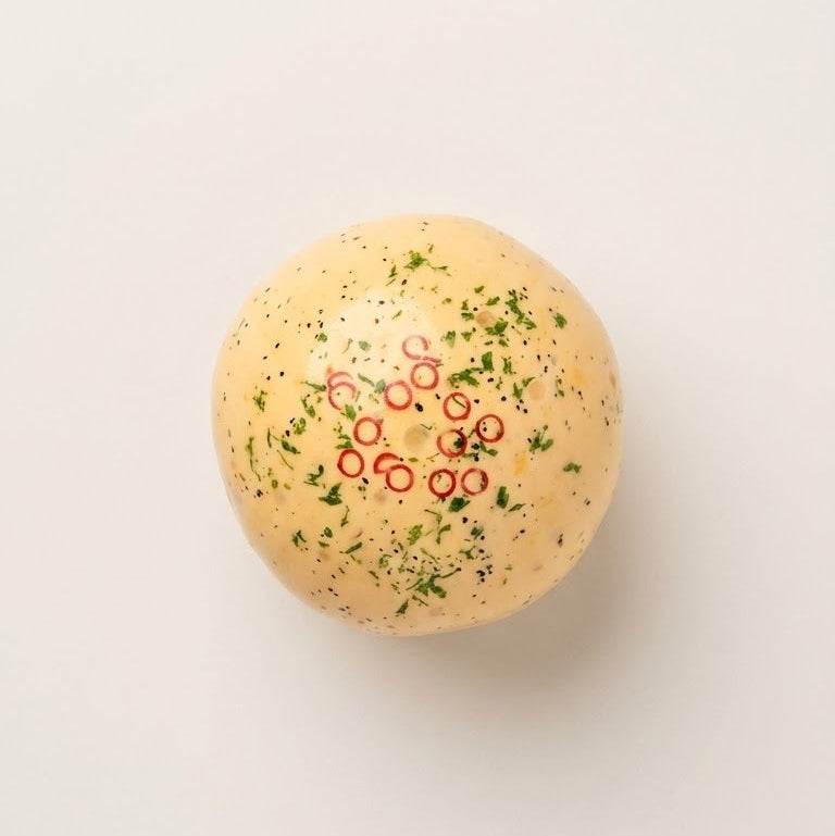 Handmade omelette squishy stress ball with cream-based filling, textured sensory pieces, green herb details, and red chili rings.