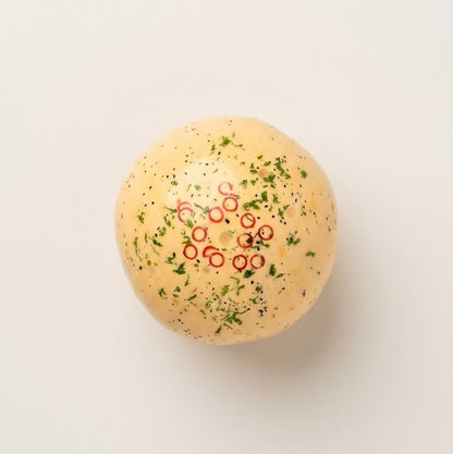 Handmade omelette squishy stress ball with cream-based filling, textured sensory pieces, green herb details, and red chili rings.
