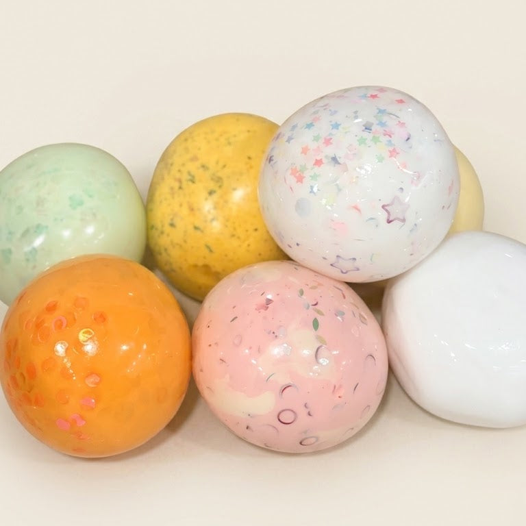 Assorted handmade squishy stress balls from the SQUU Artistic Handmade Collection with colorful sensory textures and decorative fillings.