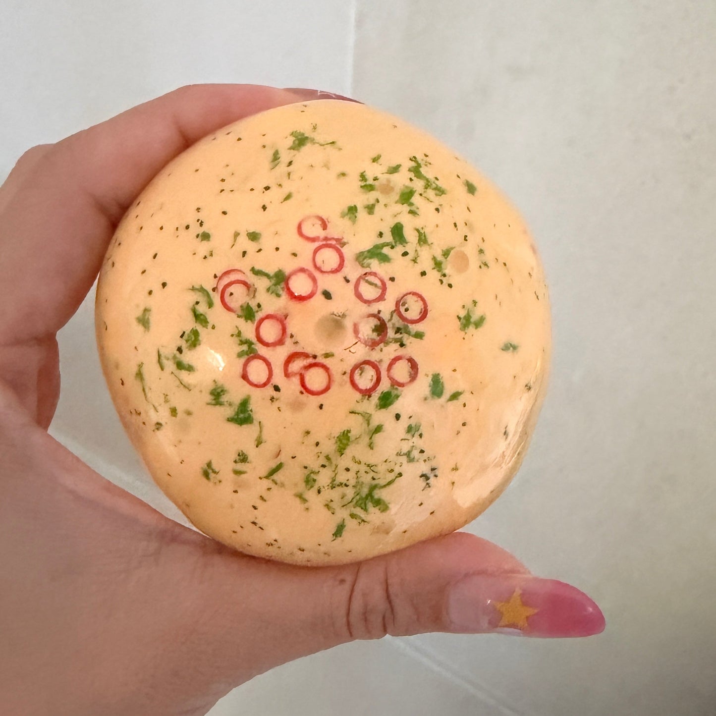 Handheld omelette squishy stress ball with cream-based filling, textured sensory pieces, green herb details, and red chili rings