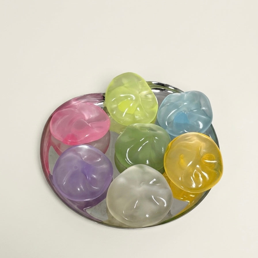 Translucent coconut oil sugar ball squishy stress toys in assorted colors arranged on a silver tray.