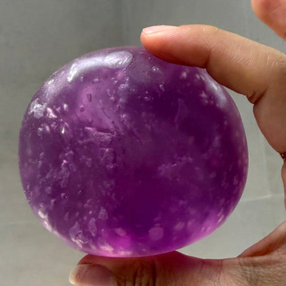 Close-up of an ultra-soft crystal purple grape squishy stress ball with zero-rebound texture and tiny air bubbles formed after repeated use.