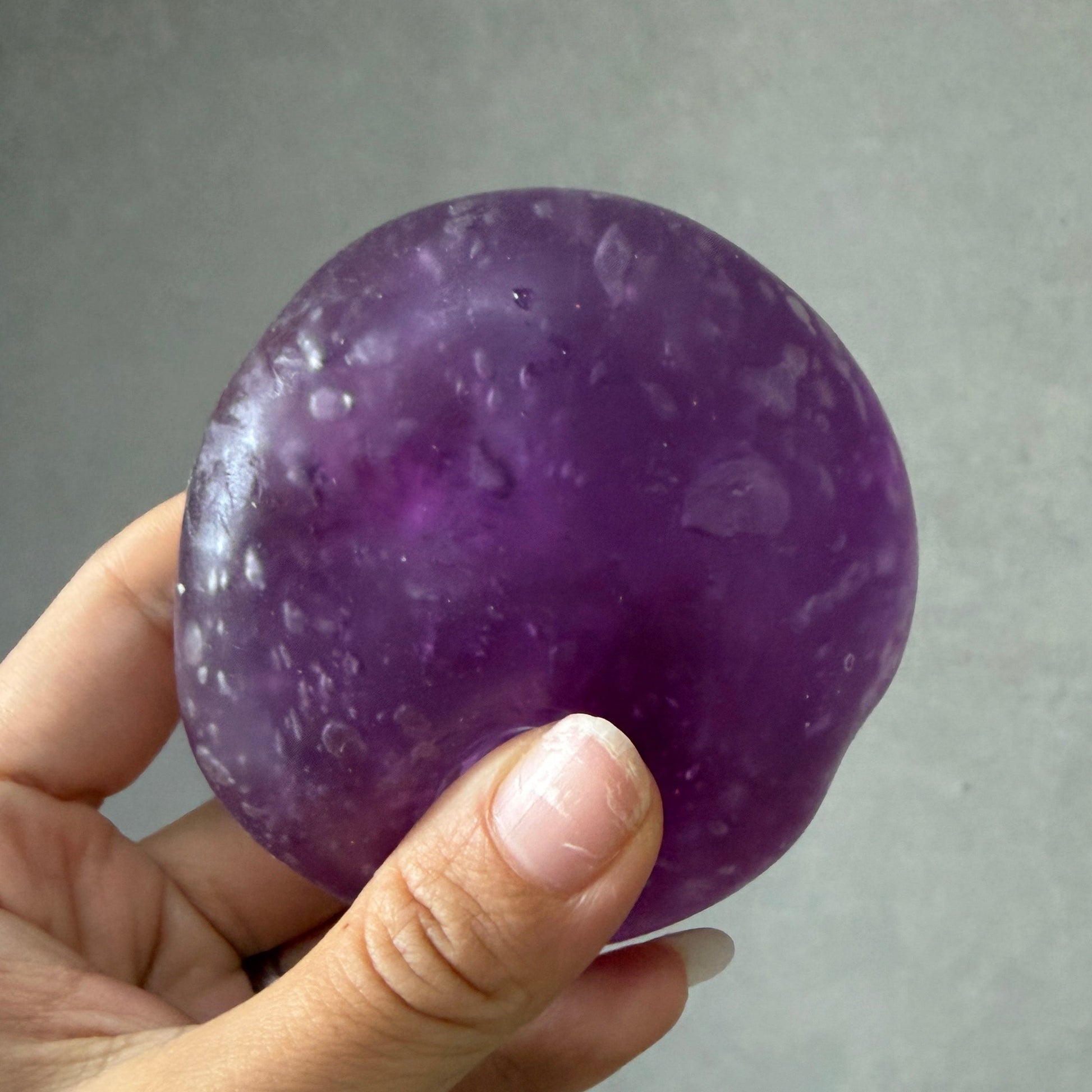 Handheld crystal purple grape squishy stress ball with zero-rebound ultra-soft texture, non-sticky surface, and tiny air bubbles formed after repeated squishing.