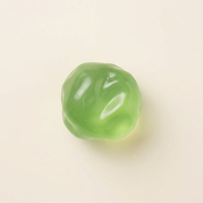 Emerald green coconut squishy stress ball with translucent finish, medium-firm resistance, dense texture, and slow rebound.
