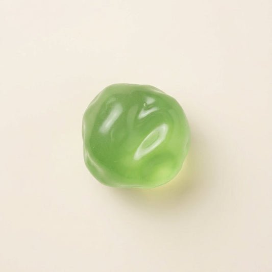 Emerald green coconut squishy stress ball with translucent finish, medium-firm resistance, dense texture, and slow rebound.
