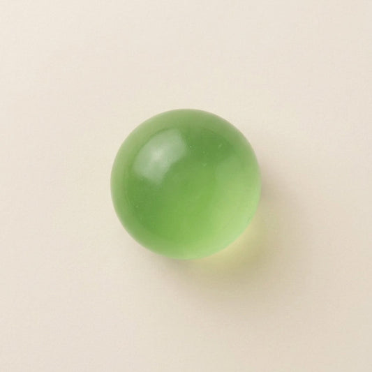 Emerald green coconut oil squishy stress ball with translucent color, smooth glossy surface, medium-firm resistance, and slow rebound.
