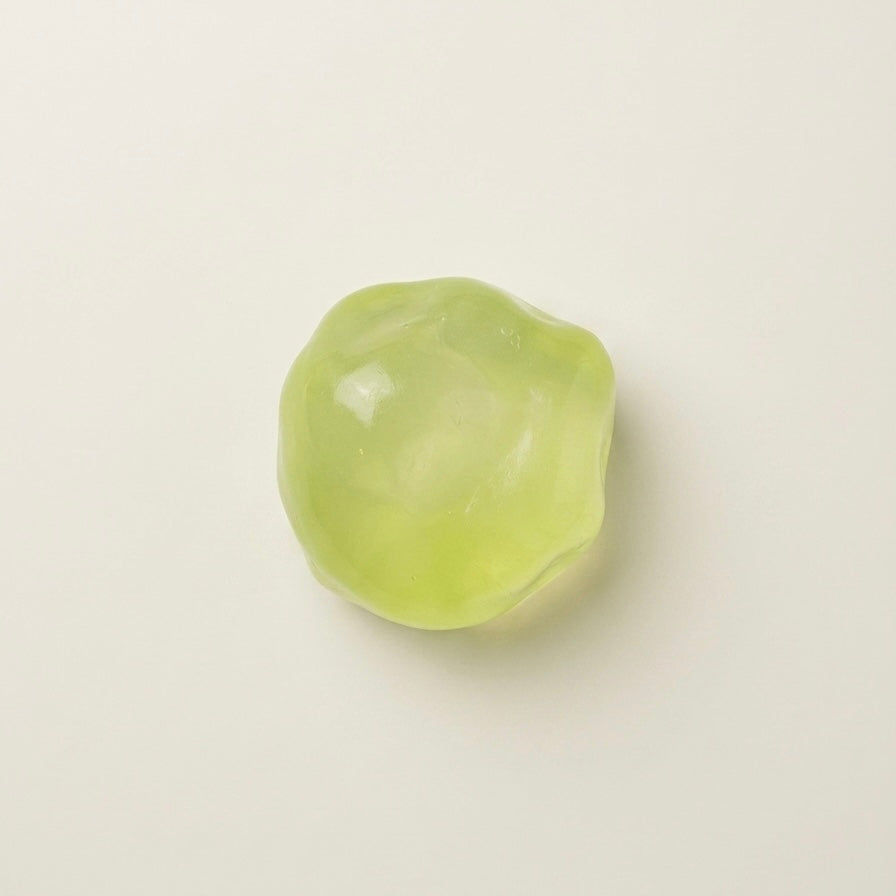 Green coconut oil sugar ball squishy stress ball with a translucent glossy finish and soft moldable texture.