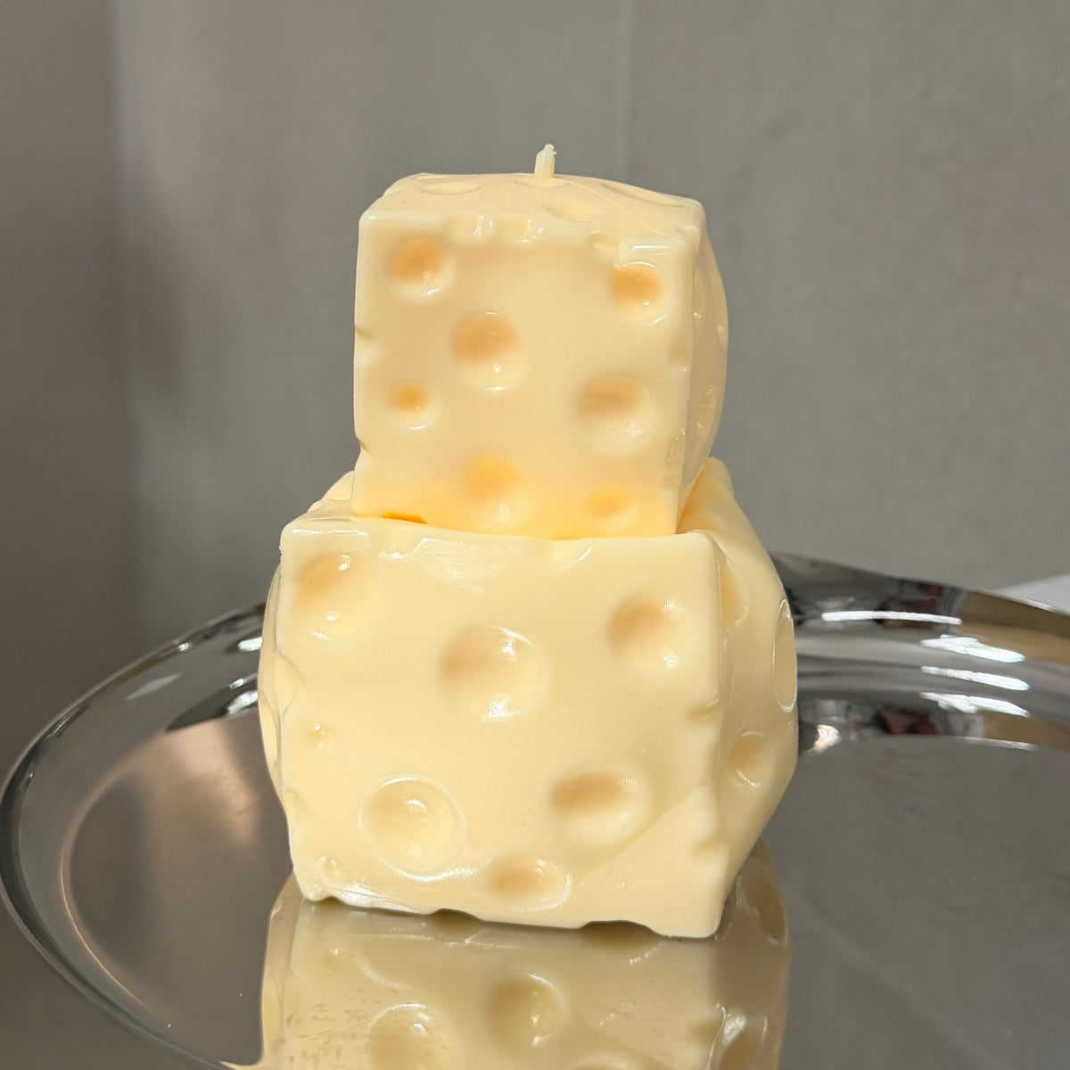 Jumbo and baby cheese squishy stress ball sensory toys stacked together on a silver tray for size comparison.