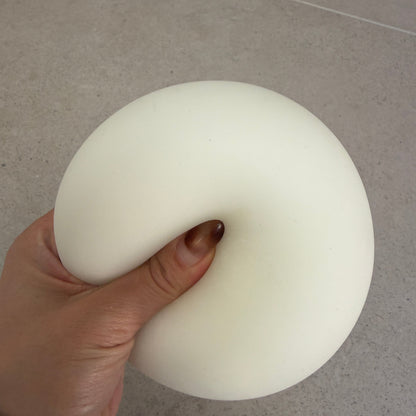 Hand squeezing a 9cm Jumbo Zen squishy stress ball with soft doughy texture, matte finish, and oversized full-hand design.