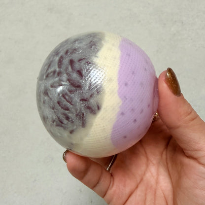 Handheld Purple Rice Taro Mochi squishy stress ball with soft chewy cream-based texture, realistic grain filling, low stickiness, and 6 cm round shape.