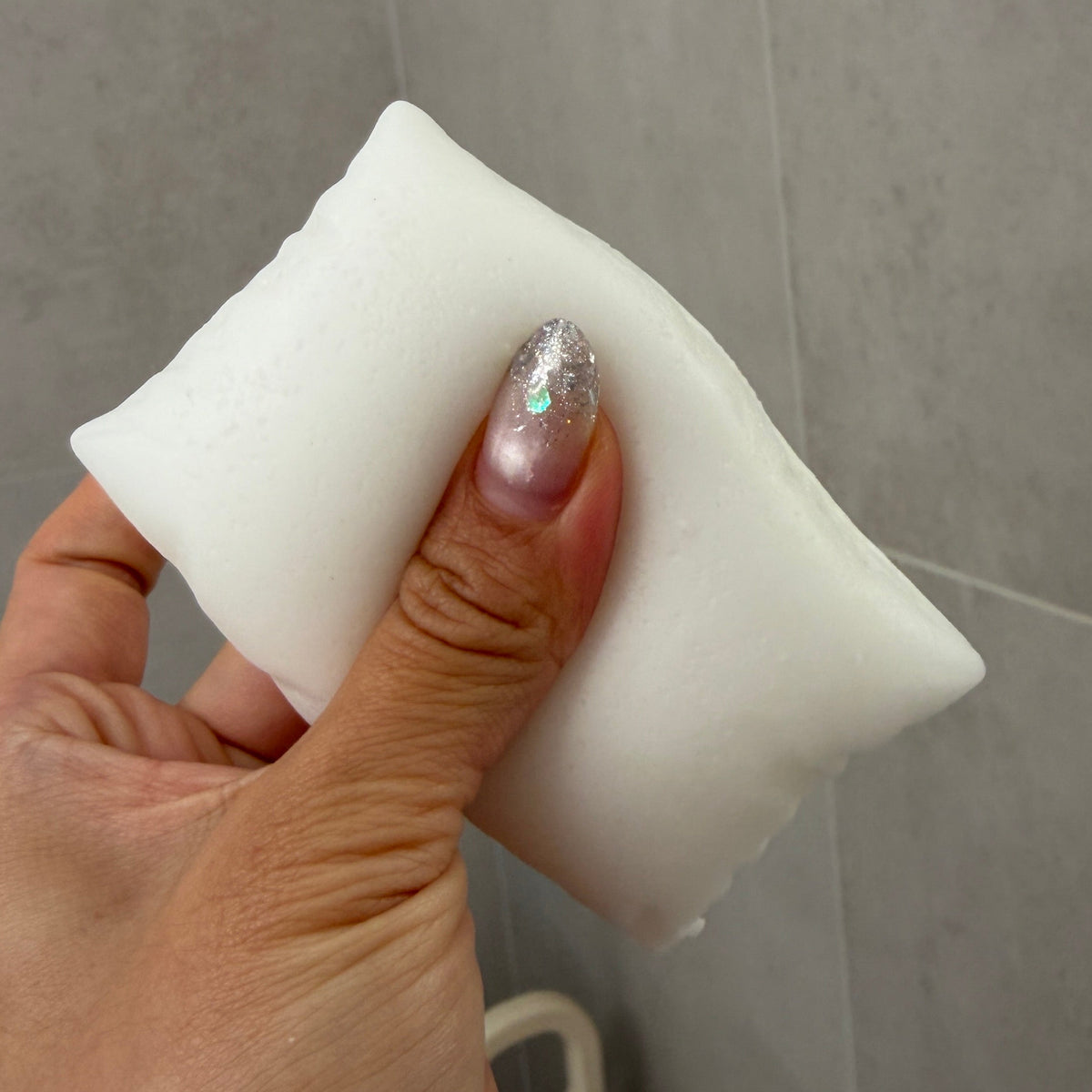 Handheld ultra-soft sticky pillow TABA squishy sensory toy showing its soft squeeze, cushion shape, and flexible texture